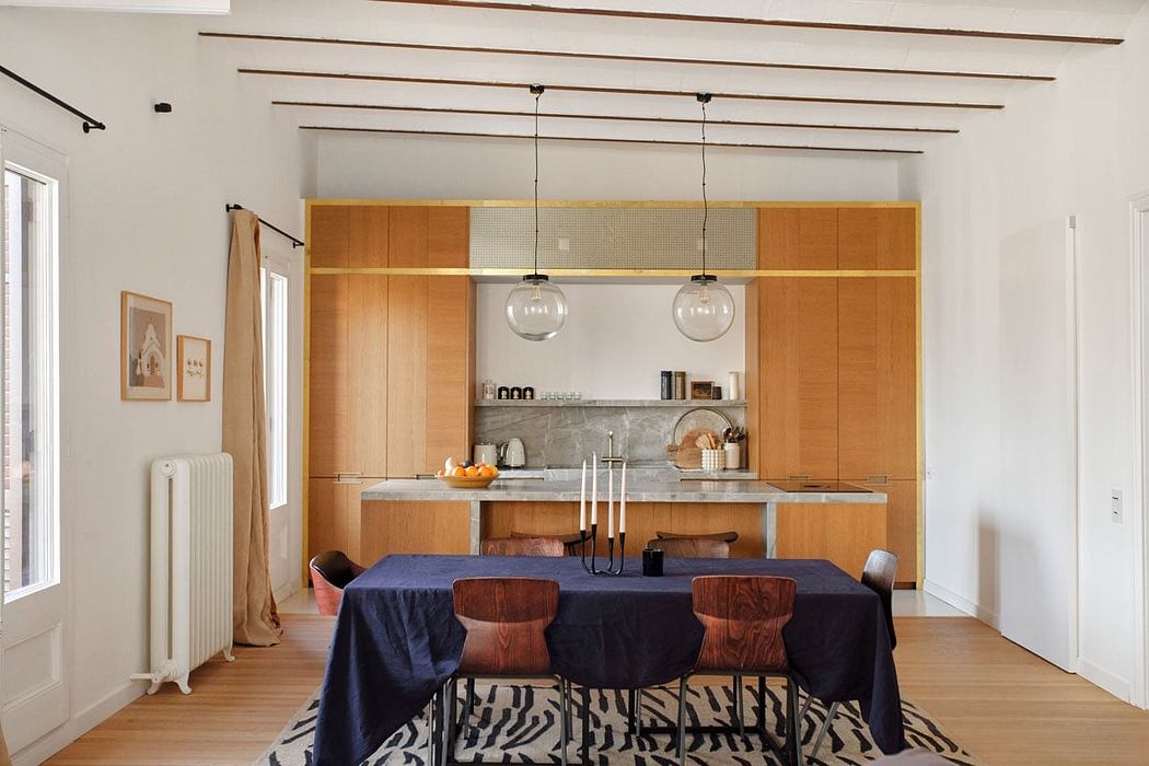 Sleek, modern kitchen with wooden cabinetry, pendant lighting, and stylish dining setup.