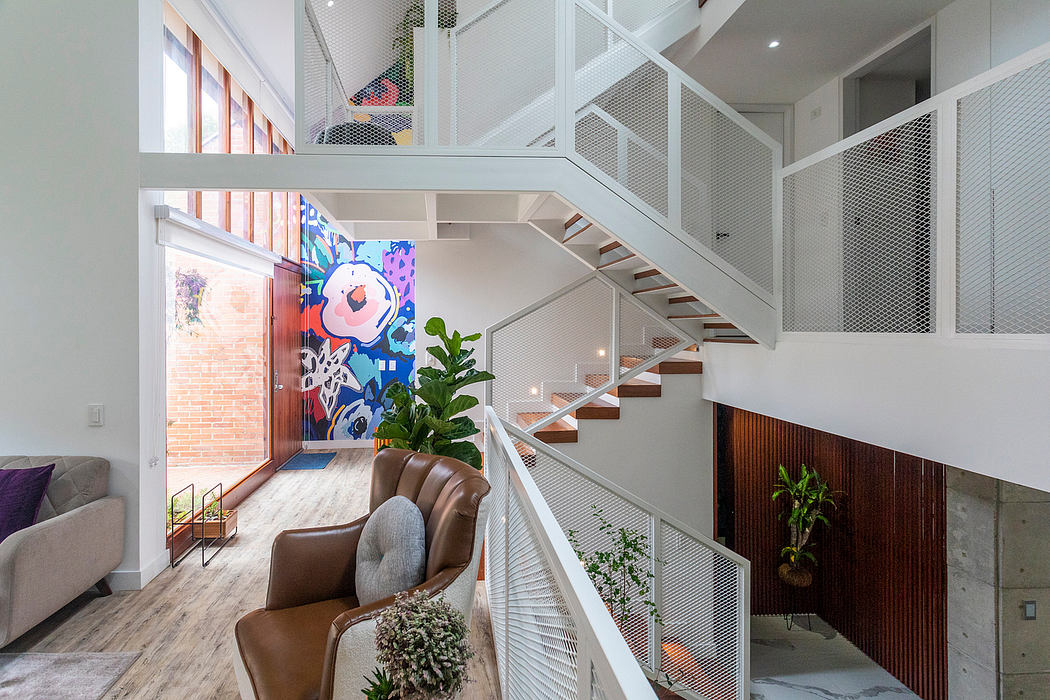 A modern, open-concept home with a colorful mural, sleek stairs, and lush greenery.