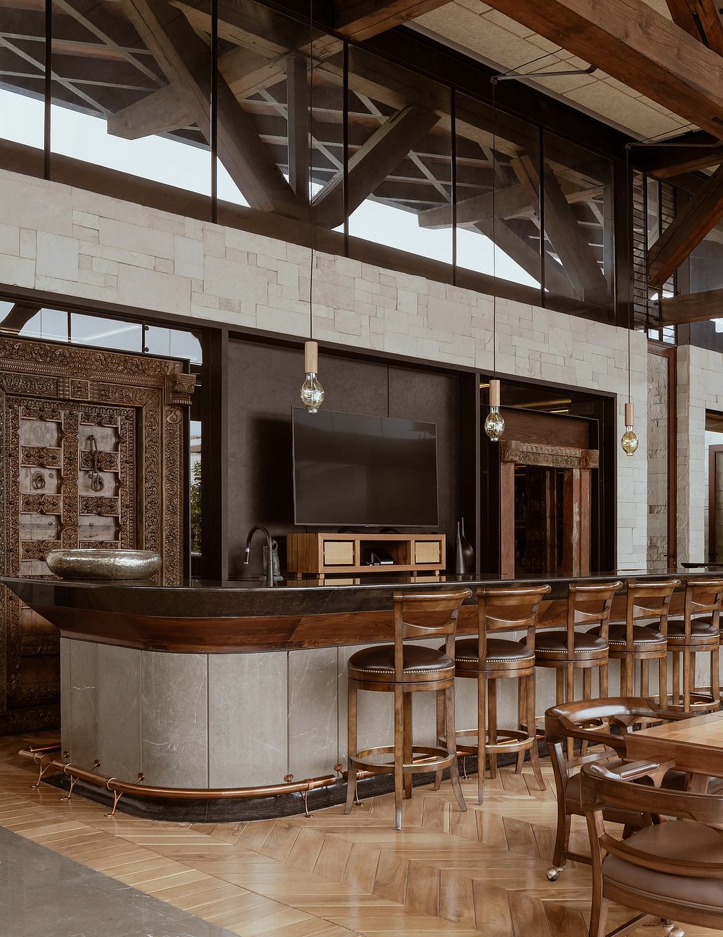 A rustic, wooden-beamed interior with a curved, stone-covered bar, wood-paneled walls, and ornate light fixtures.