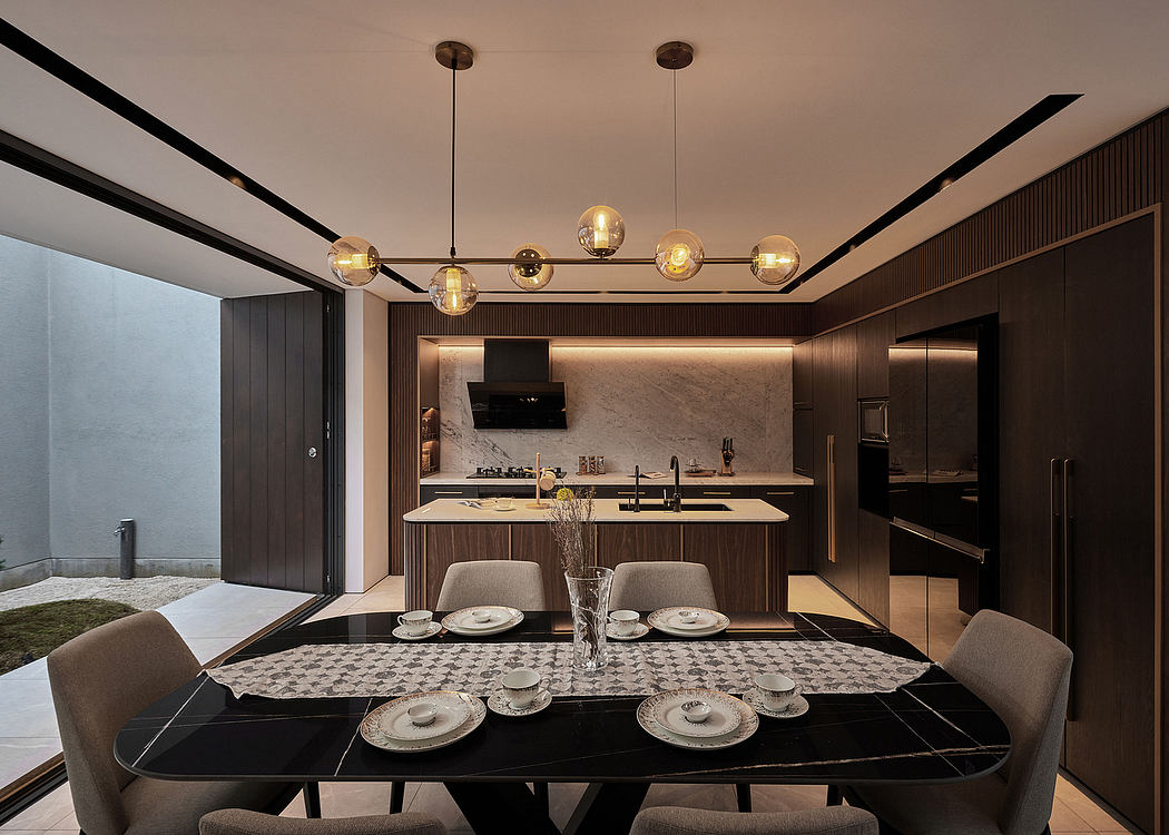 Modern, warm-toned kitchen and dining area with sleek, dark wood cabinetry and large pendant lighting fixtures.