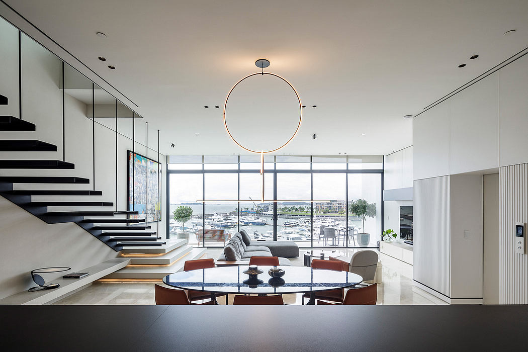 Sleek, modern living space with stunning floor-to-ceiling windows, dramatic staircase, and stylish furnishings.