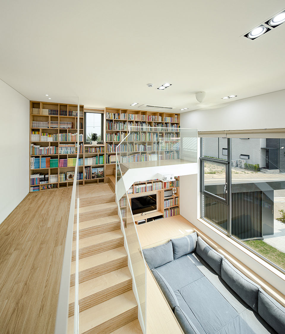 Minimalist living room with large built-in bookshelves, wooden stairs, and modern furniture.