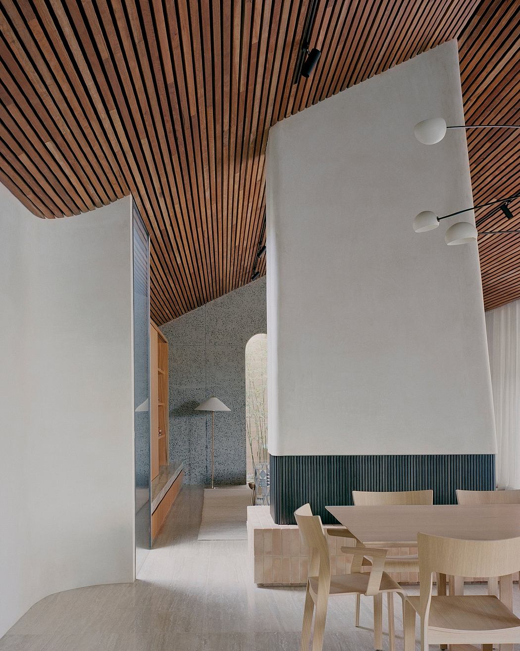 Sleek wood paneling, geometric lighting, and minimalist furnishings create a modern, inviting space.