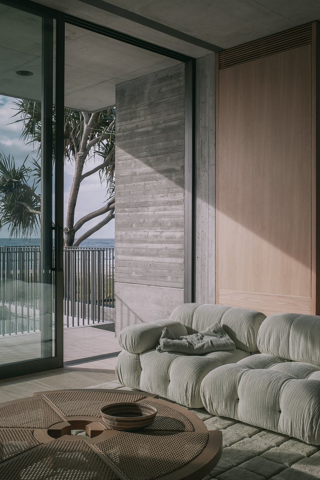 Spacious living room with concrete walls, glass doors, and a plush gray sofa.