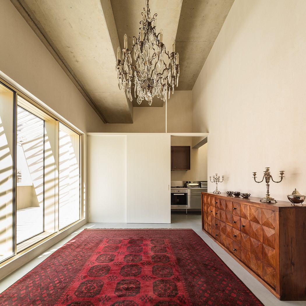 Spacious room with a grand crystal chandelier, wooden furniture, and patterned area rug.