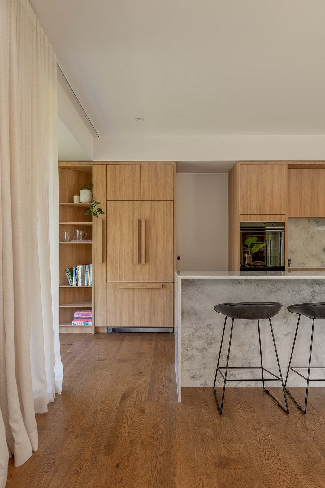 Well-designed modern kitchen with wood cabinetry, marble countertop, and sleek bar stools.