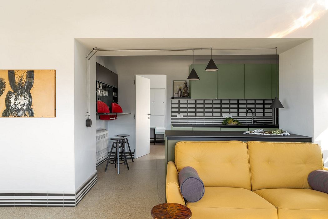 Modern open-concept apartment with sleek kitchen, yellow sofa, and industrial accents.