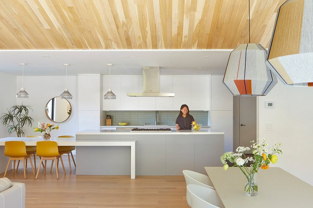 Open-concept kitchen with modern appliances, wood-paneled walls, and a mix of white and yellow furnishings.
