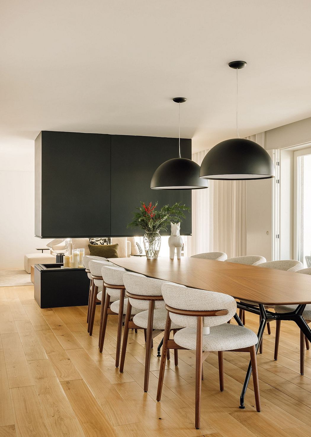 Sleek, modern dining room with black pendant lights, wood table, and upholstered chairs.