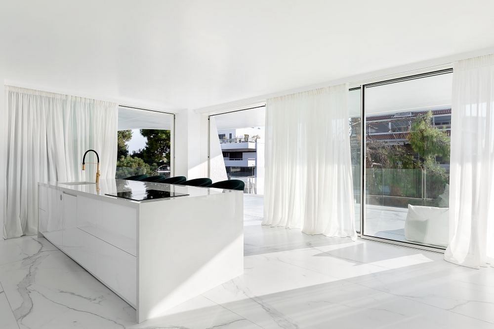 Sleek, modern kitchen with marble countertops, large windows, and minimalist design.
