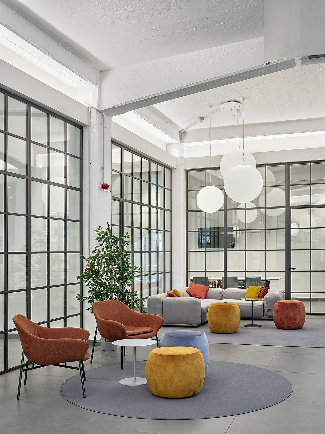 Spacious open-plan lounge with large windows, modern furniture, and hanging light fixtures.