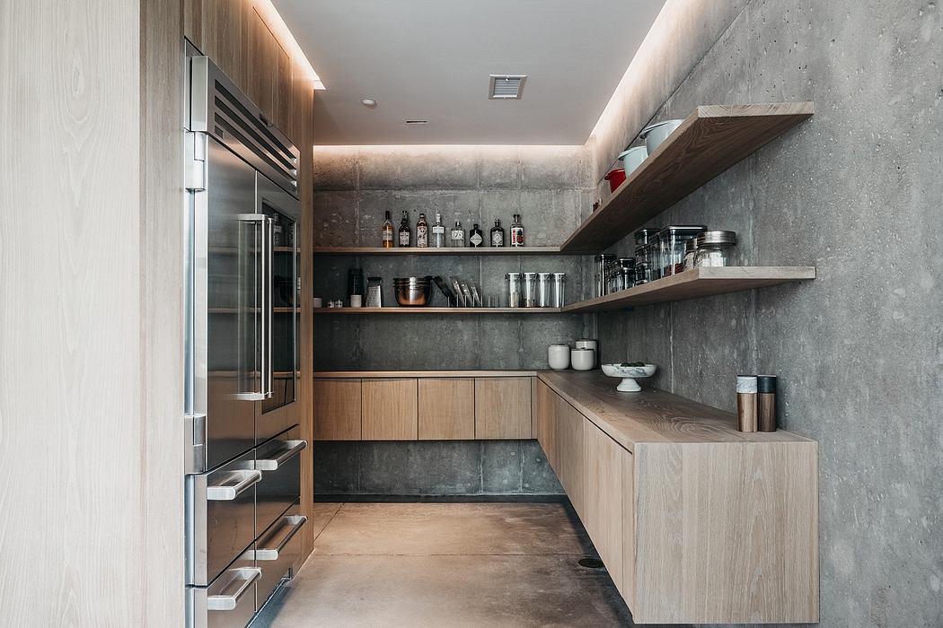 Sleek, modern kitchen with concrete walls, wood cabinetry, and floating shelves displaying glassware.