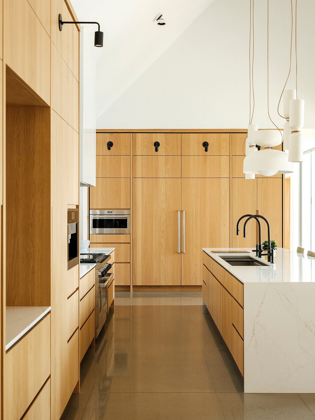 A modern kitchen with sleek wood cabinetry, stainless steel appliances, and a marble countertop.