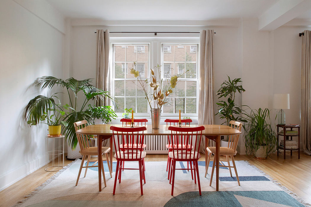Well-appointed modern dining room with natural wood table, red chairs, and lush greenery.