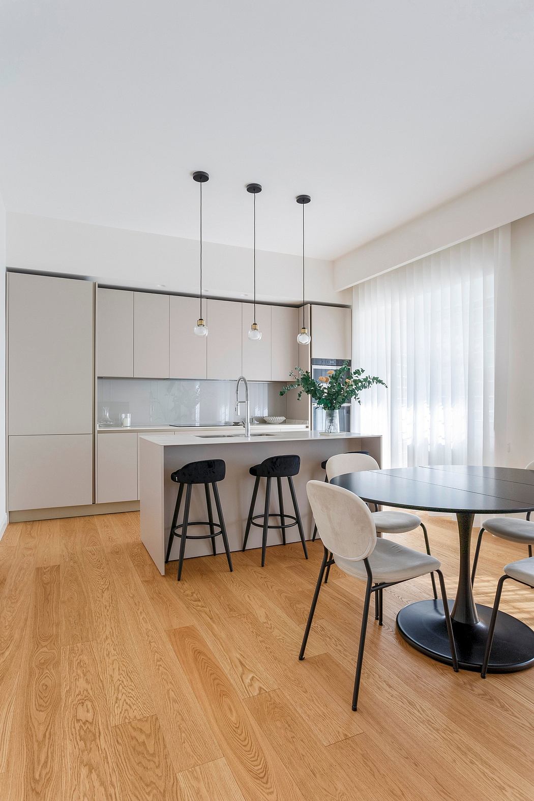 Minimalist kitchen with sleek gray cabinets, black pendant lights, and wood flooring.