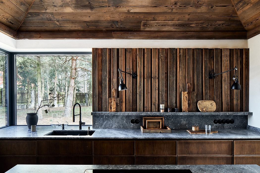 Rustic kitchen with wooden walls, dark stone countertops, and minimalist pendant lights.