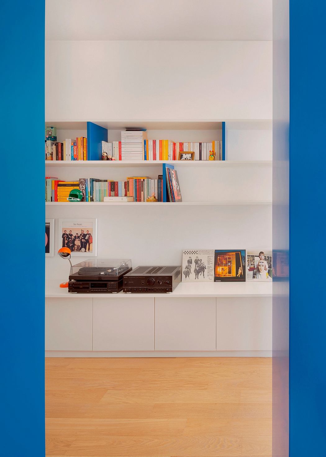 Built-in shelves showcase a vibrant book collection and sound system against a blue accent wall.