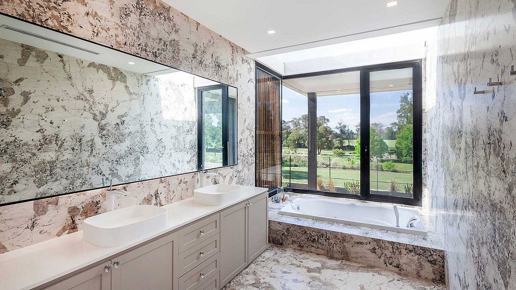 Luxurious bathroom with marble walls, double vanity, and expansive outdoor view.