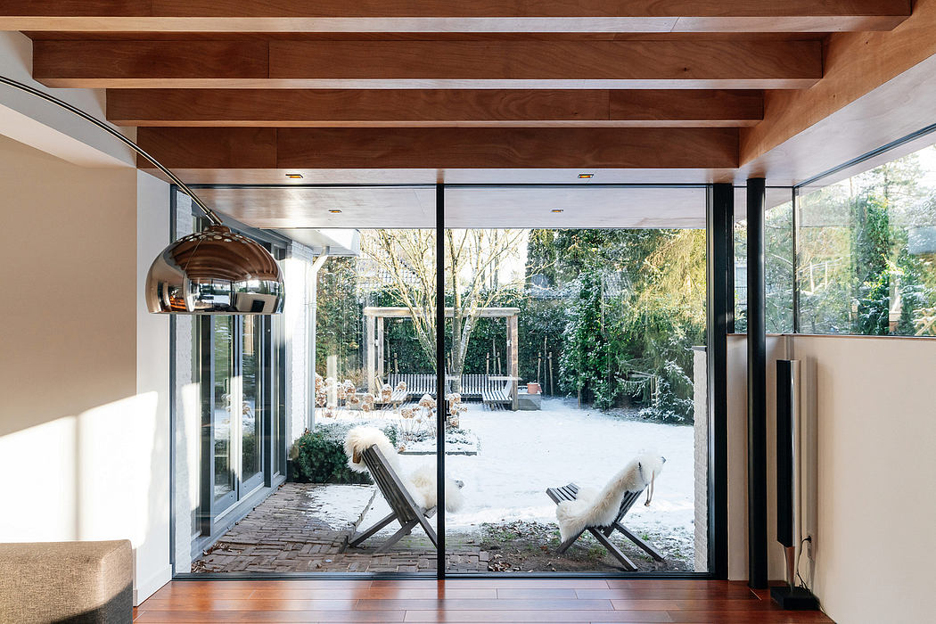 Expansive glass walls, wood beams, and a cozy winter scene outside create a serene interior.