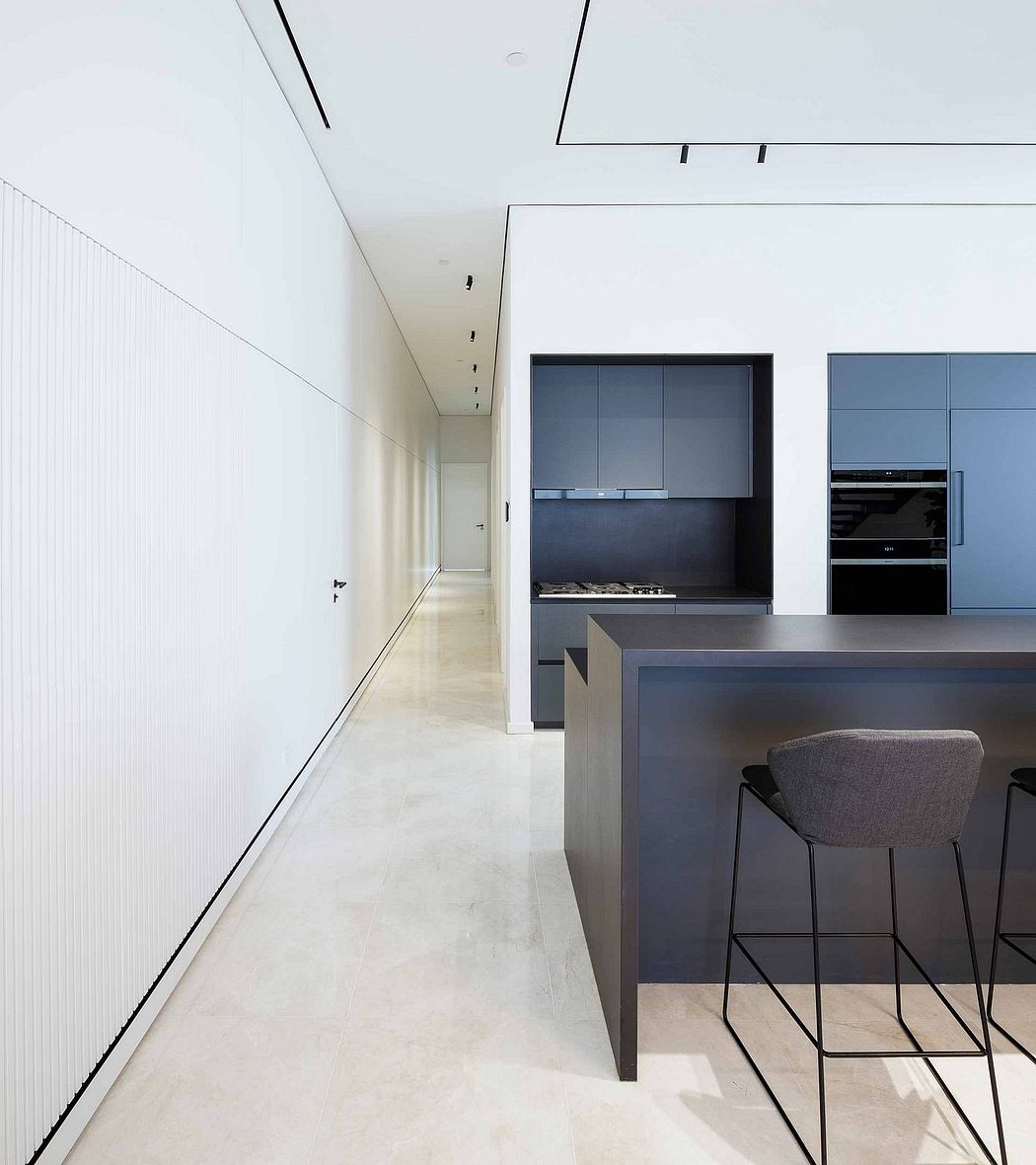 A modern, minimalist kitchen with clean lines, grey cabinetry, and a long, narrow hallway.