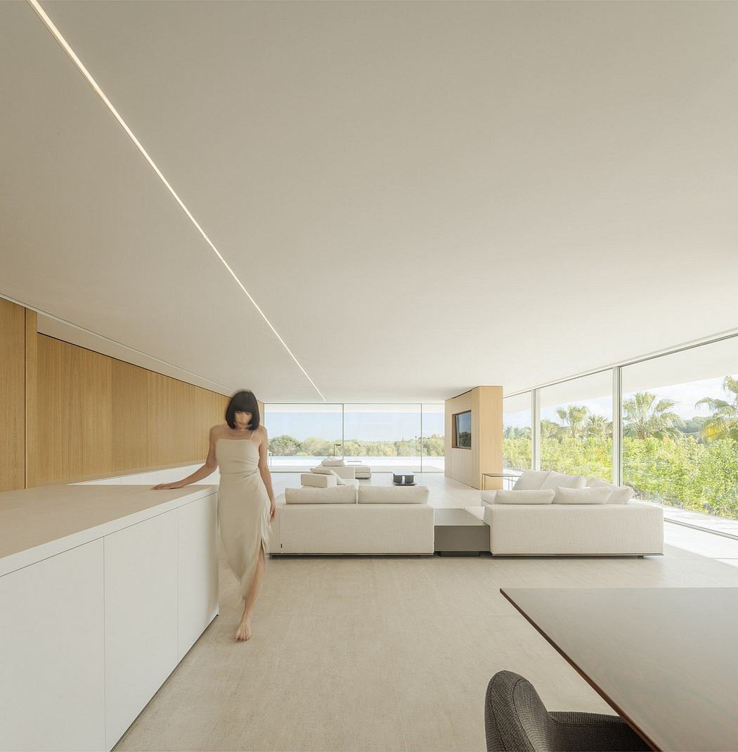 Sleek, modern living room with panoramic windows, minimalist furniture, and a person in a flowing dress.