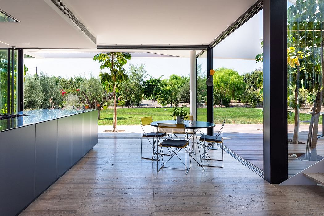 Modern kitchen and dining area with large windows overlooking lush garden landscape.
