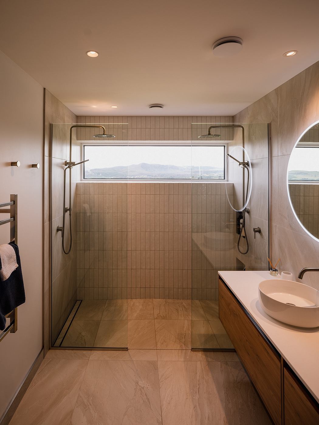 Elegant bathroom with large window, dual showerheads, and modern vanity fixture.