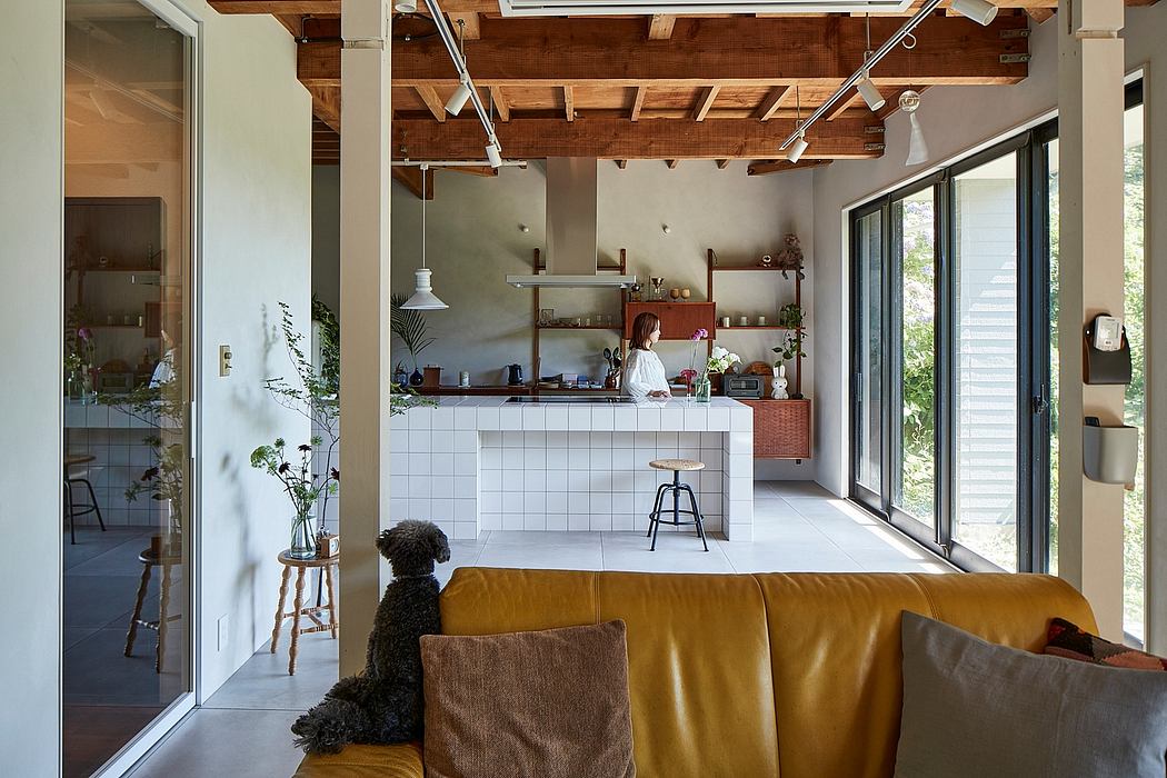 Rustic kitchen with exposed wooden beams, tile countertops, and large windows overlooking nature.