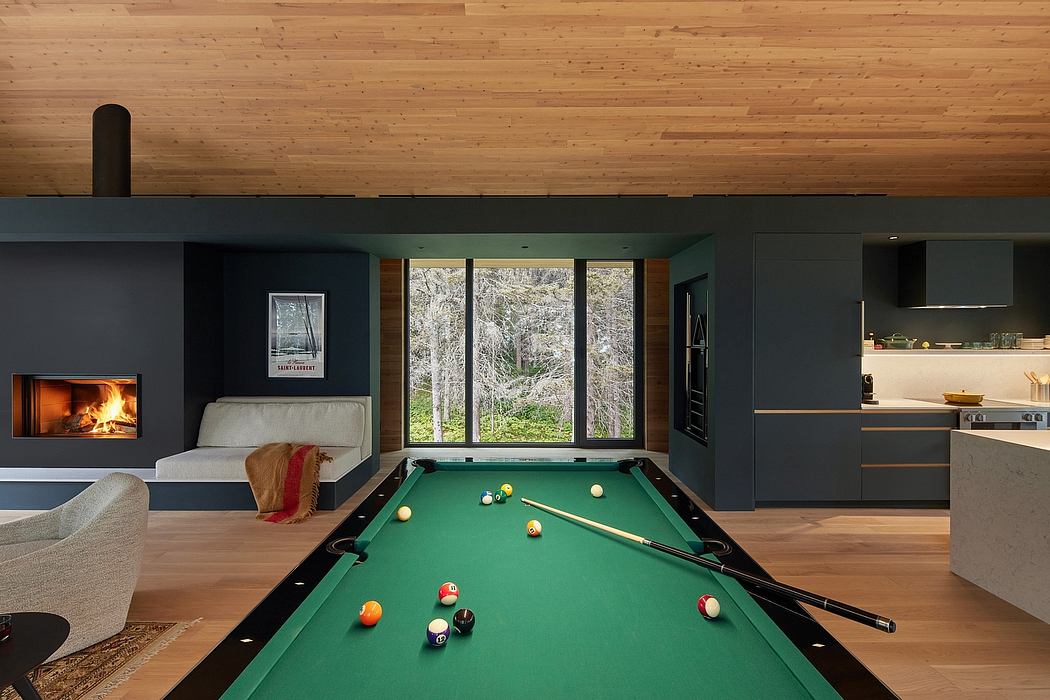 Cozy cabin interior with a fireplace, pool table, and expansive windows offering scenic views.