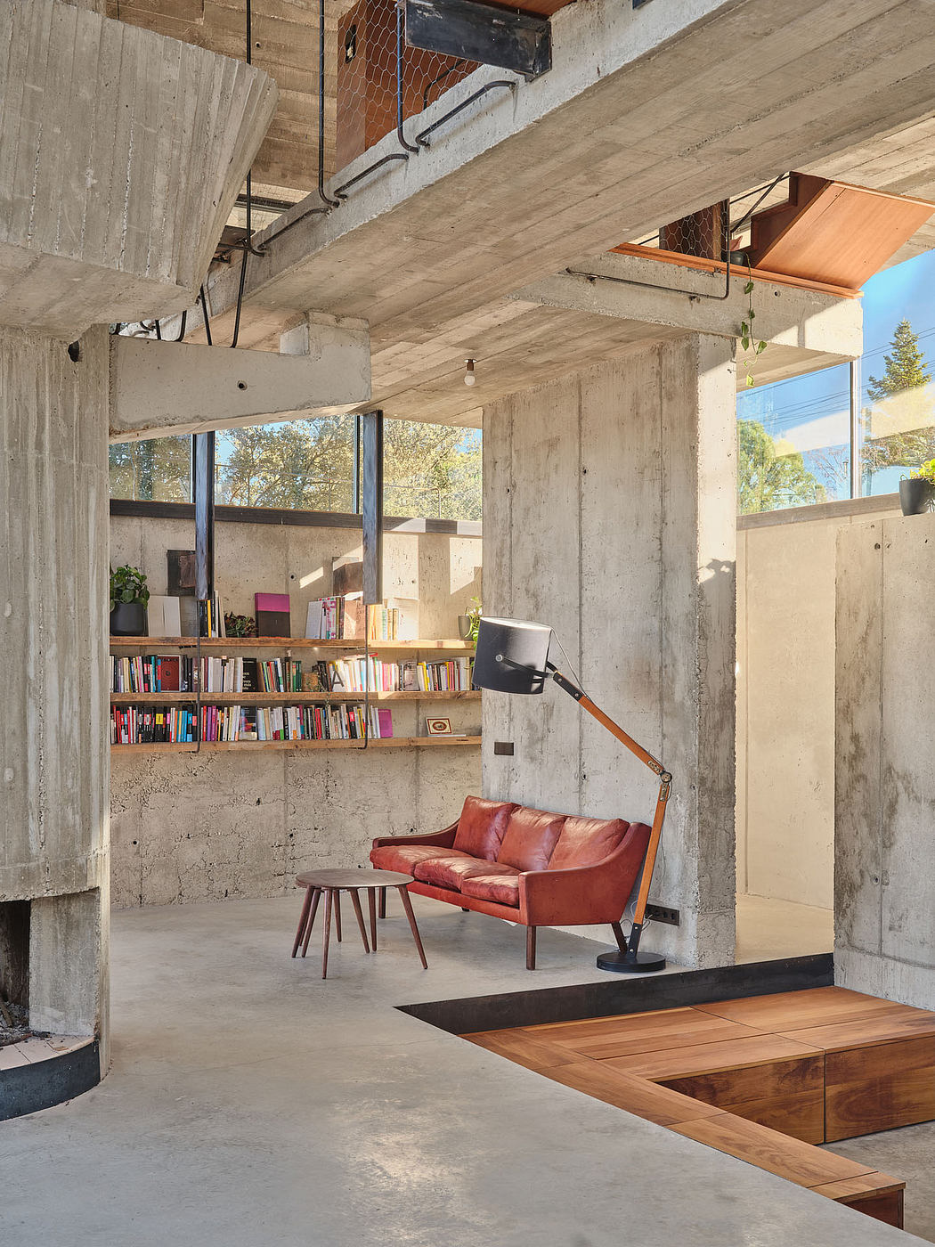 Cozy, industrial-style living space with exposed concrete, wood, and a built-in bookshelves.