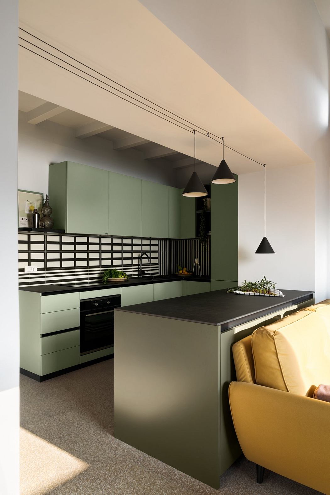 Modern kitchen with sleek green cabinetry, black countertop, and unique lighting fixtures.