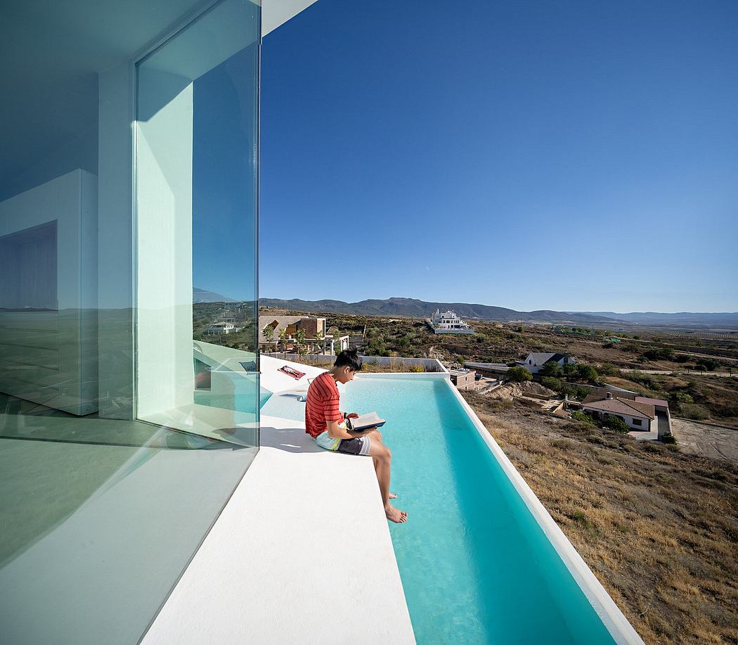 Striking modern architecture with sleek glass walls, infinity pool, and scenic view.