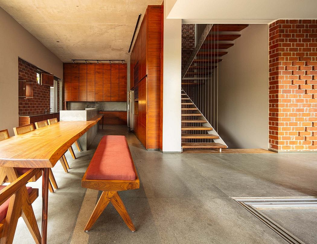 A modern kitchen and dining area with exposed brick walls, wooden furniture, and a concrete floor.