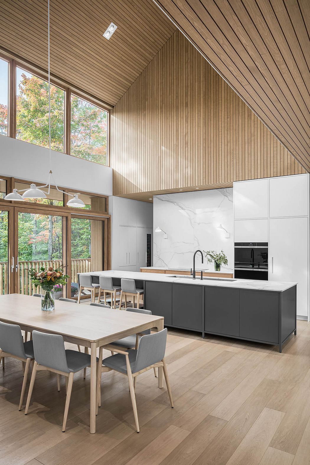 Spacious, open-concept kitchen with wooden paneled ceilings, floor-to-ceiling windows, and modern appliances.