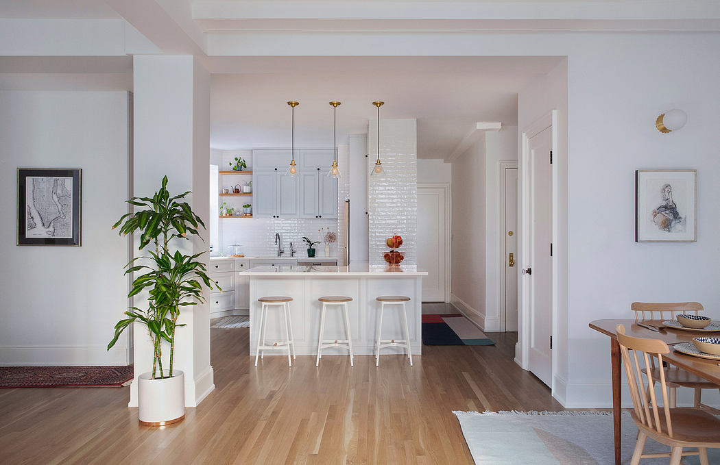 Bright, open-concept kitchen with white cabinetry, gold pendant lights, and hardwood floors.
