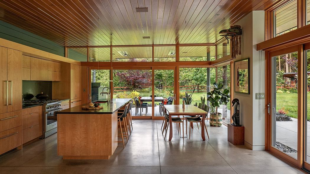 Warm-toned kitchen and dining room, with wooden accents, large windows, and natural views.