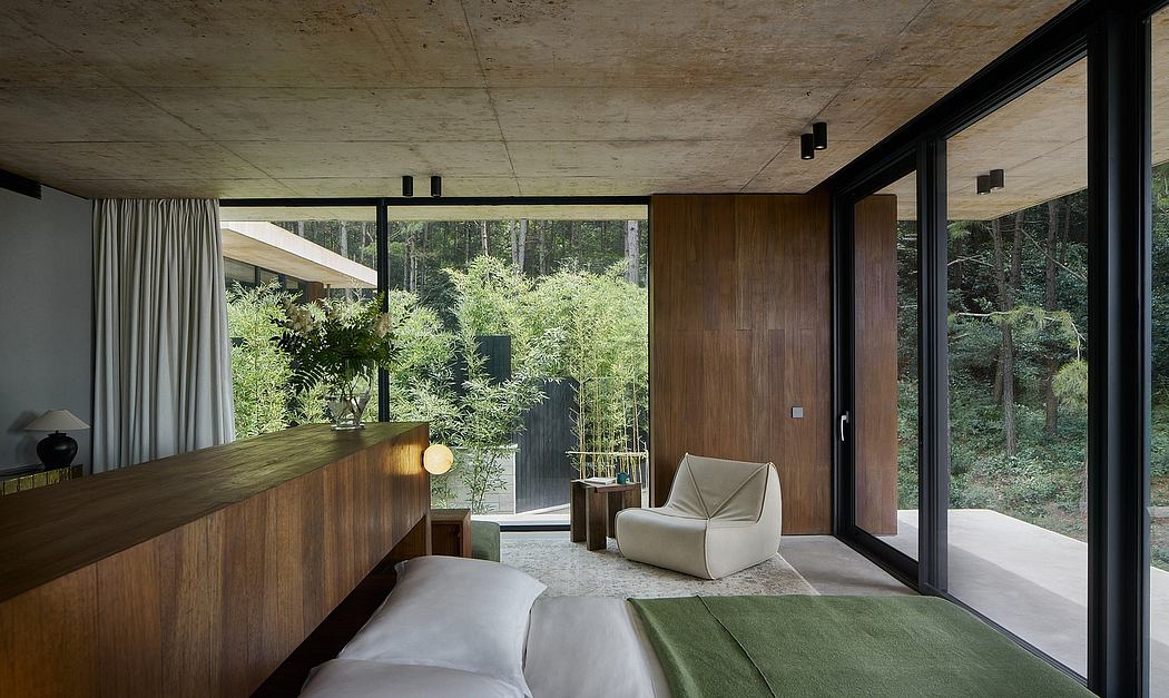 Serene, minimalist bedroom with floor-to-ceiling windows overlooking lush forest.