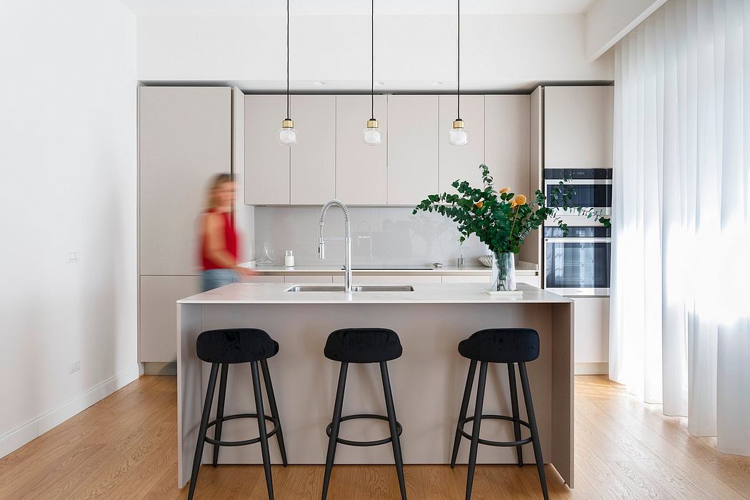 Well-lit modern kitchen with sleek gray cabinets, pendant lights, and a central island with black stools.