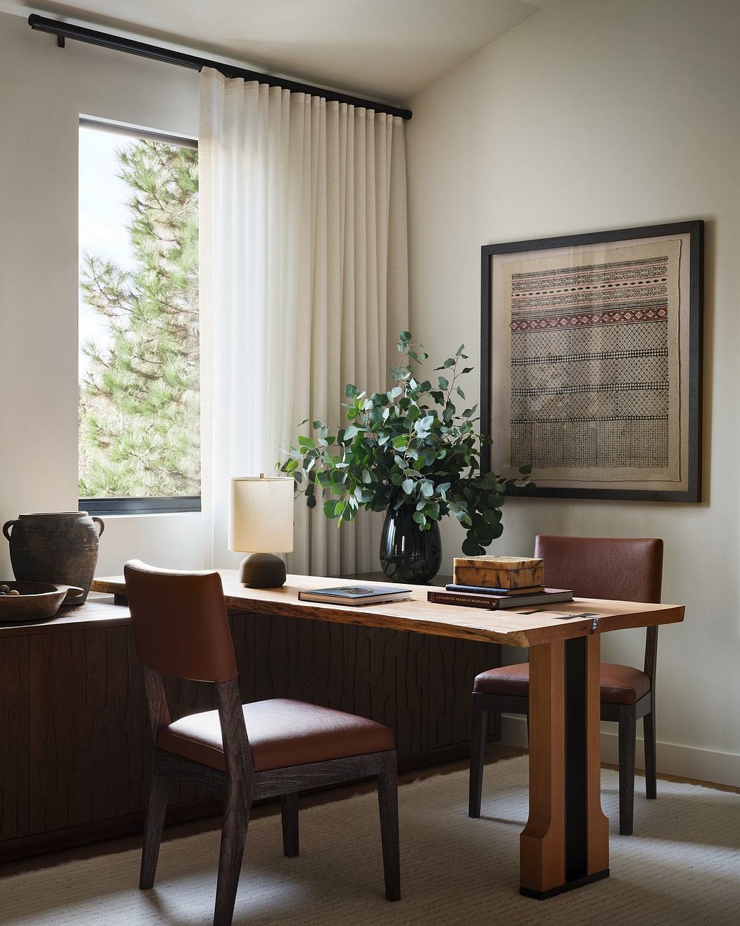 Rustic, earthy-toned dining space with wooden furniture, artwork, and potted plants.