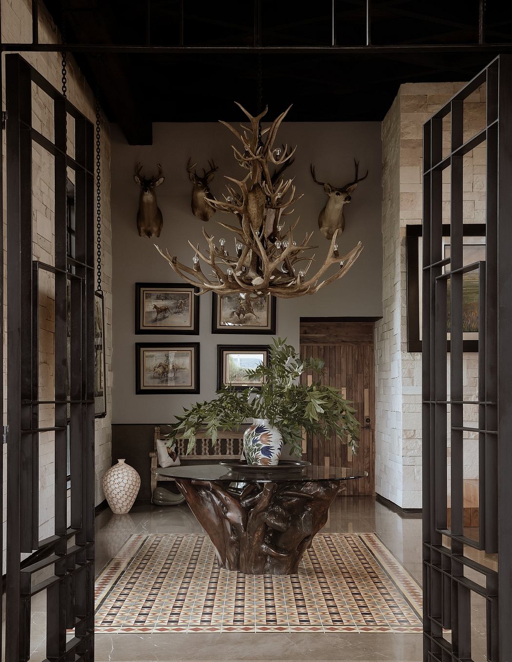 Rustic entryway with antler chandelier, wood beams, and textured tiled floor.