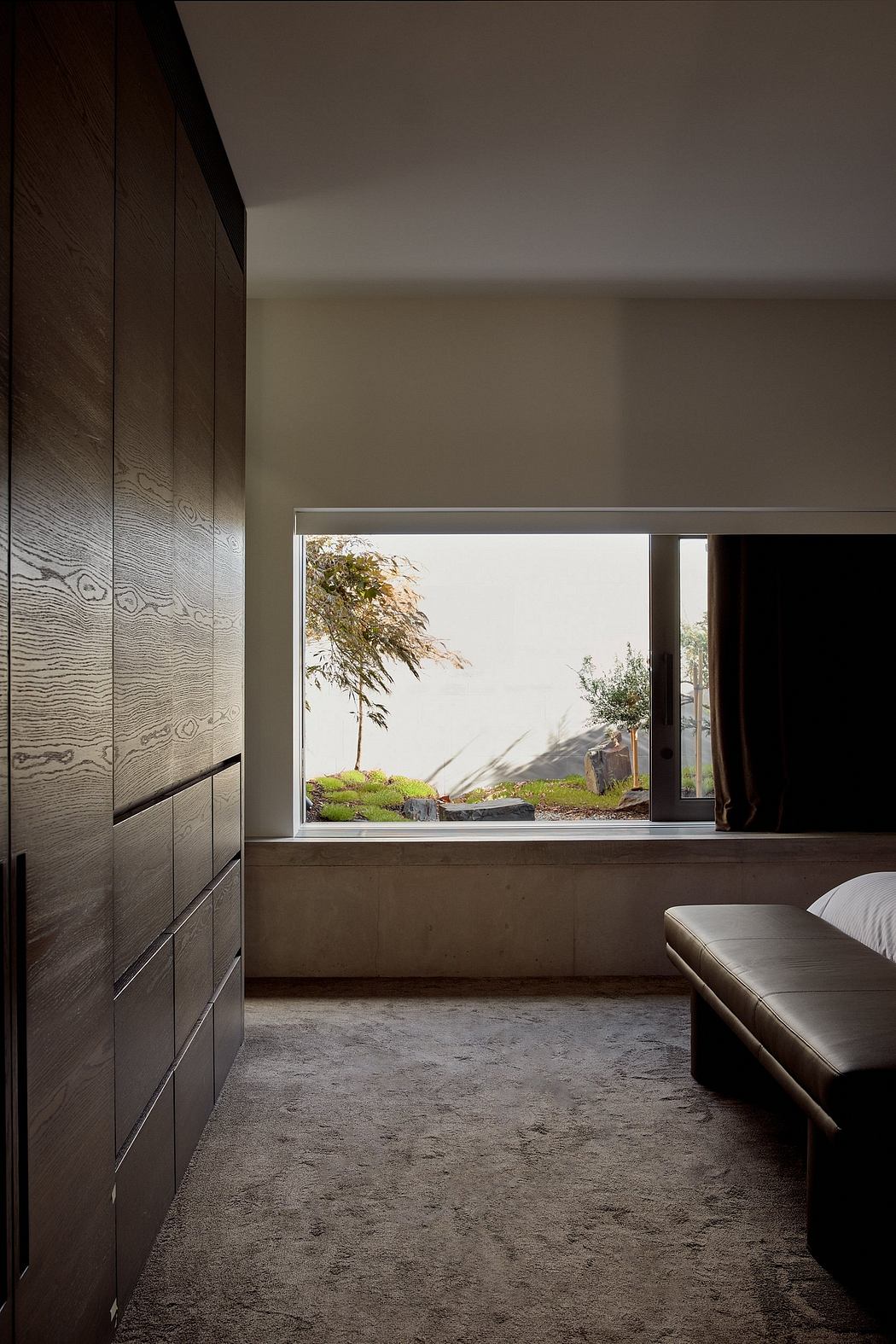 Dark wooden cabinets, concrete floor, and a large window overlooking a lush, natural setting.