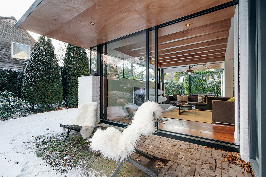 Expansive glass walls, wooden beams, and cozy seating create a warm, modern space.
