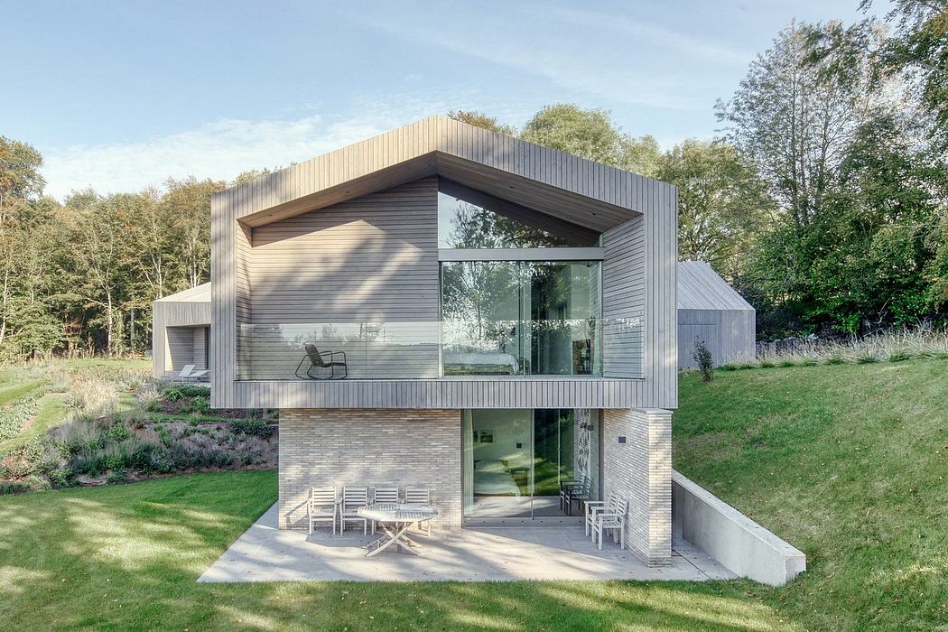 Sleek, modern structure with glass walls, wood and brick exterior, surrounded by nature.