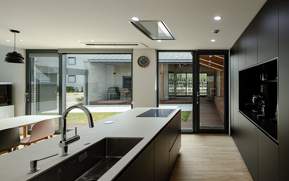 Modern kitchen with sleek cabinets, large windows, and an open floor plan leading to a patio.