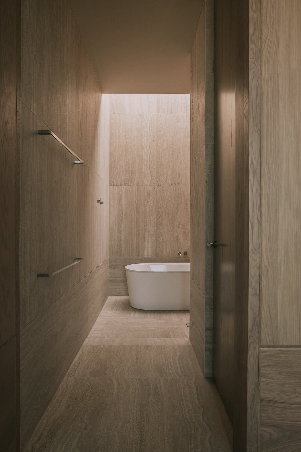 A minimalist bathroom with clean lines, a free-standing tub, and wood-paneled walls.