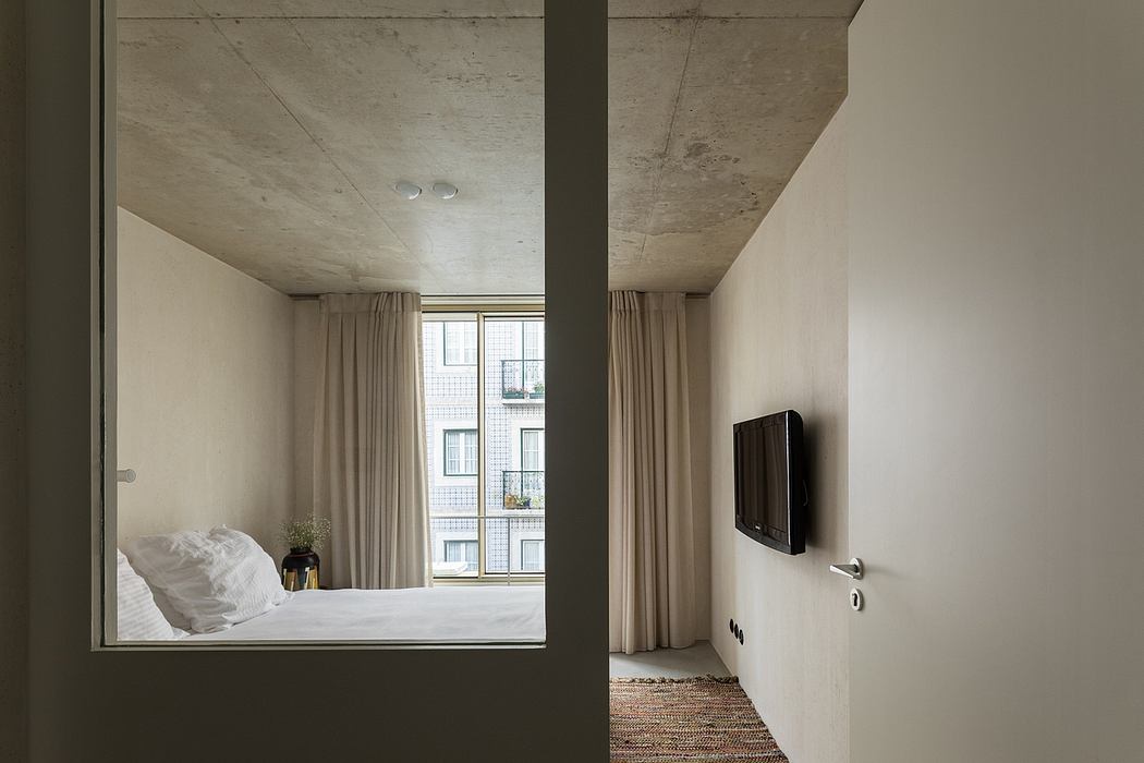 Minimalist bedroom with concrete ceiling, recessed lighting, and textured rug.