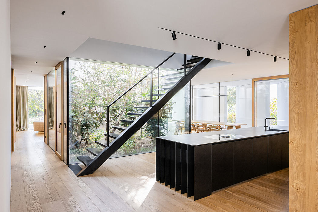 Striking modern architecture with sleek glass walls, a black metal staircase, and a wood-accented kitchen.