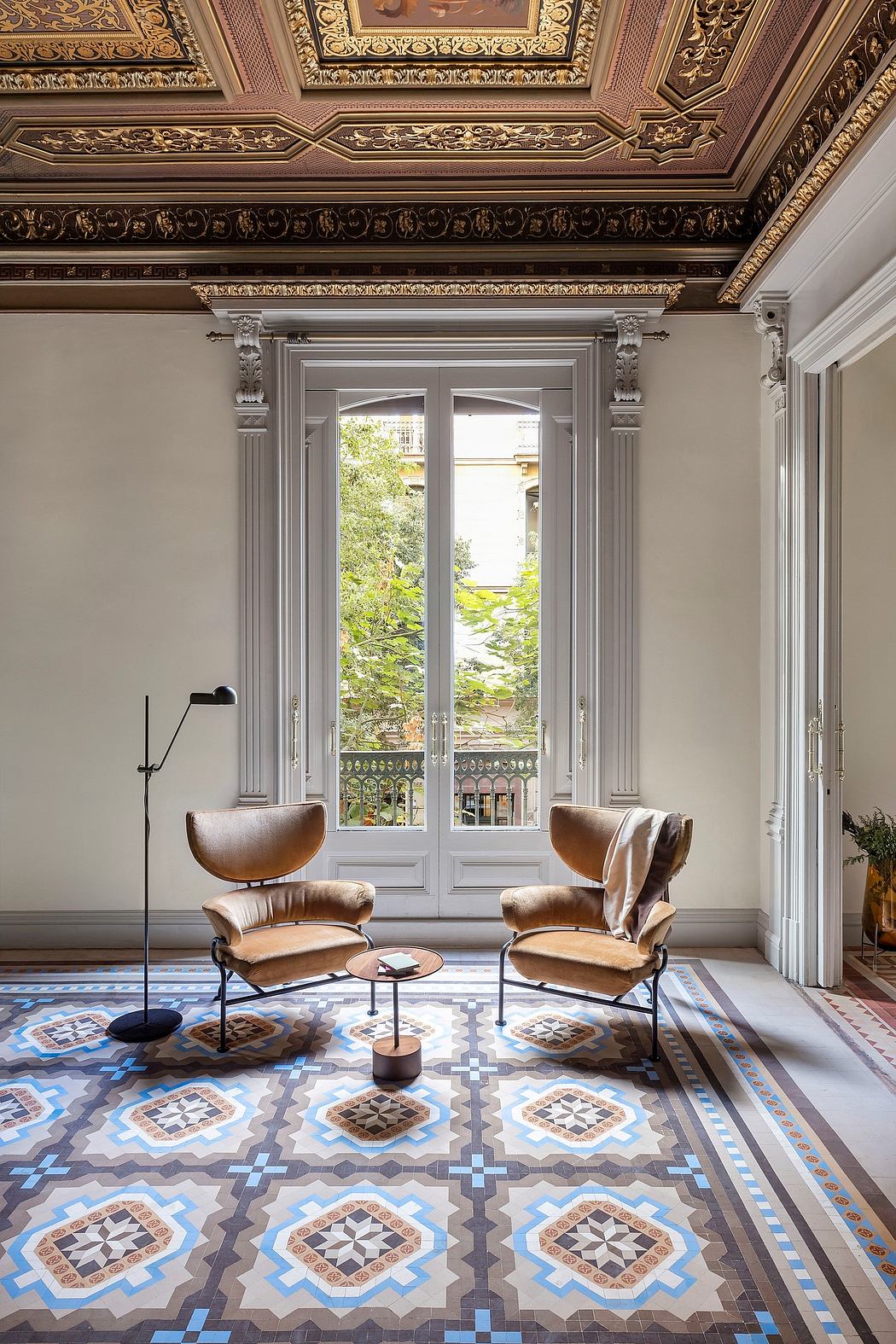 Ornate, gilded ceiling frames intricate mosaic floor tiles and leather armchairs.