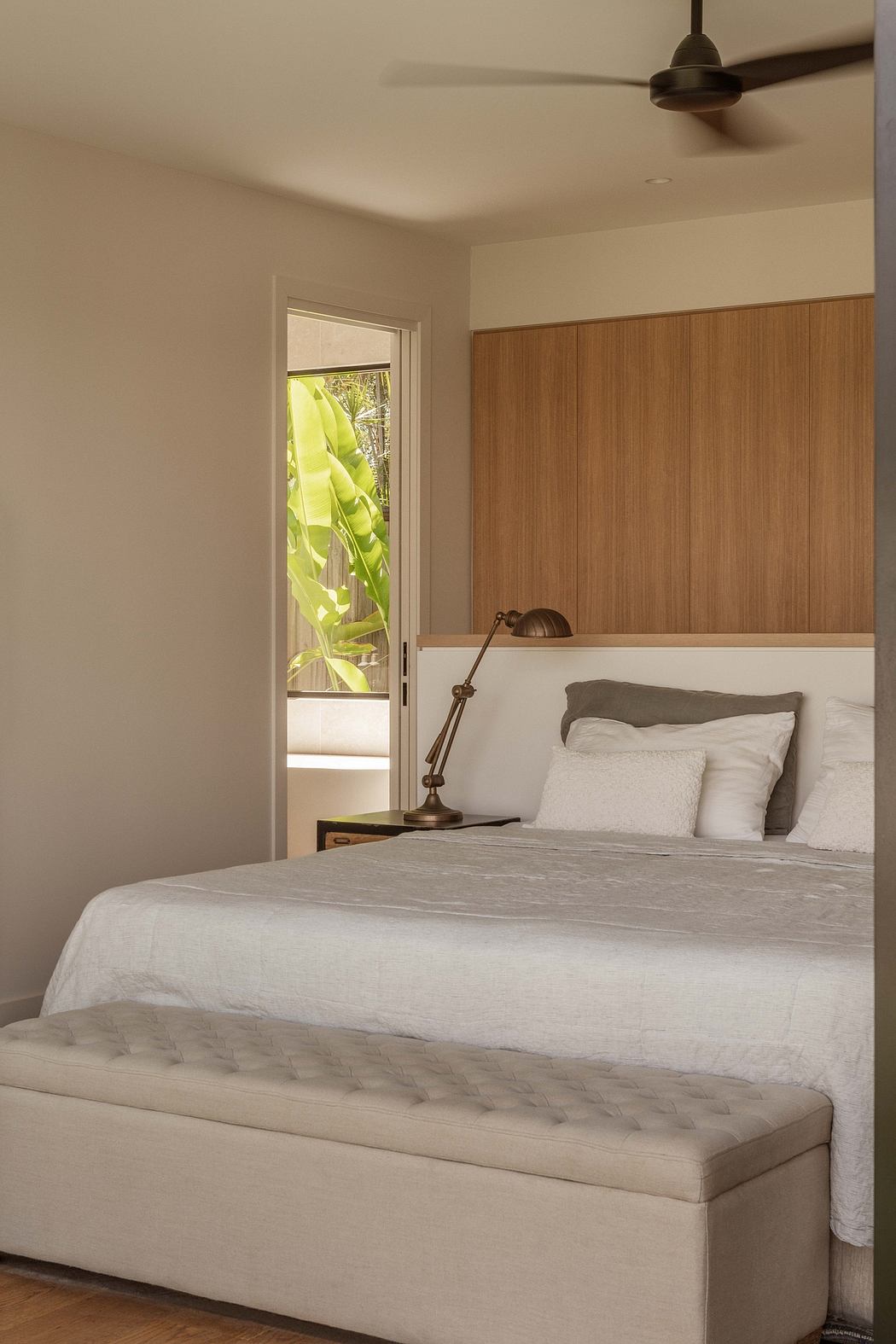 Cozy bedroom with warm wood paneling, plush bedding, and a view of lush greenery.
