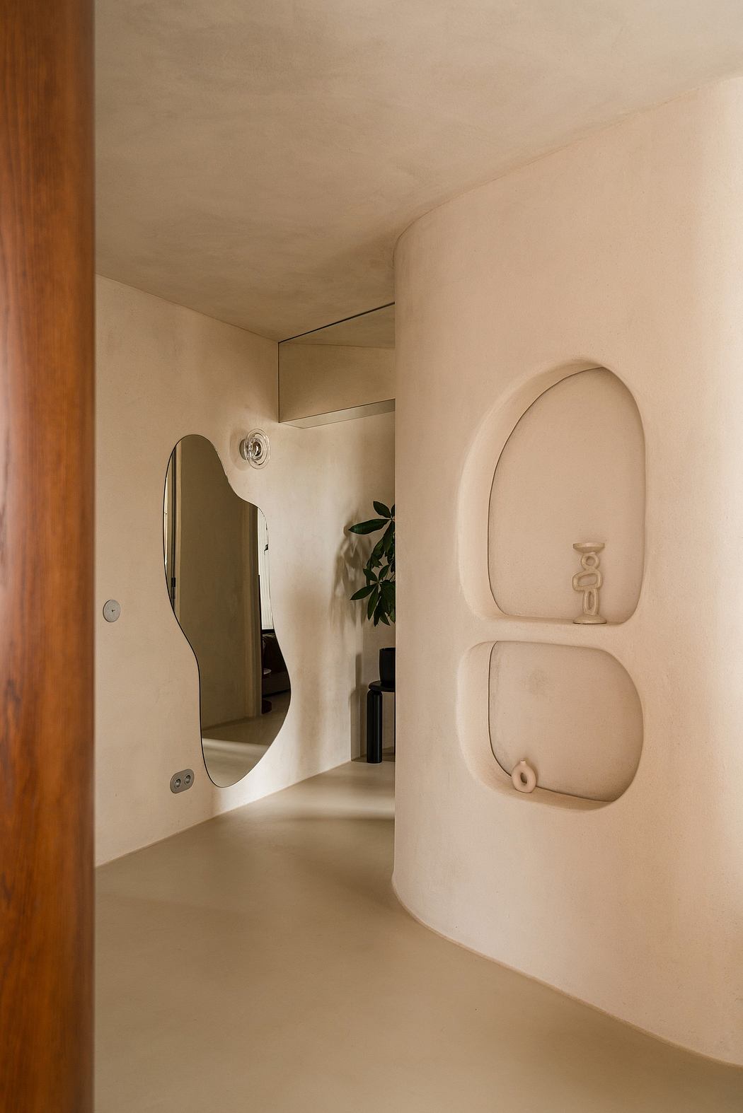 Minimalist bathroom design with curved mirror, toilet, and arched niche.